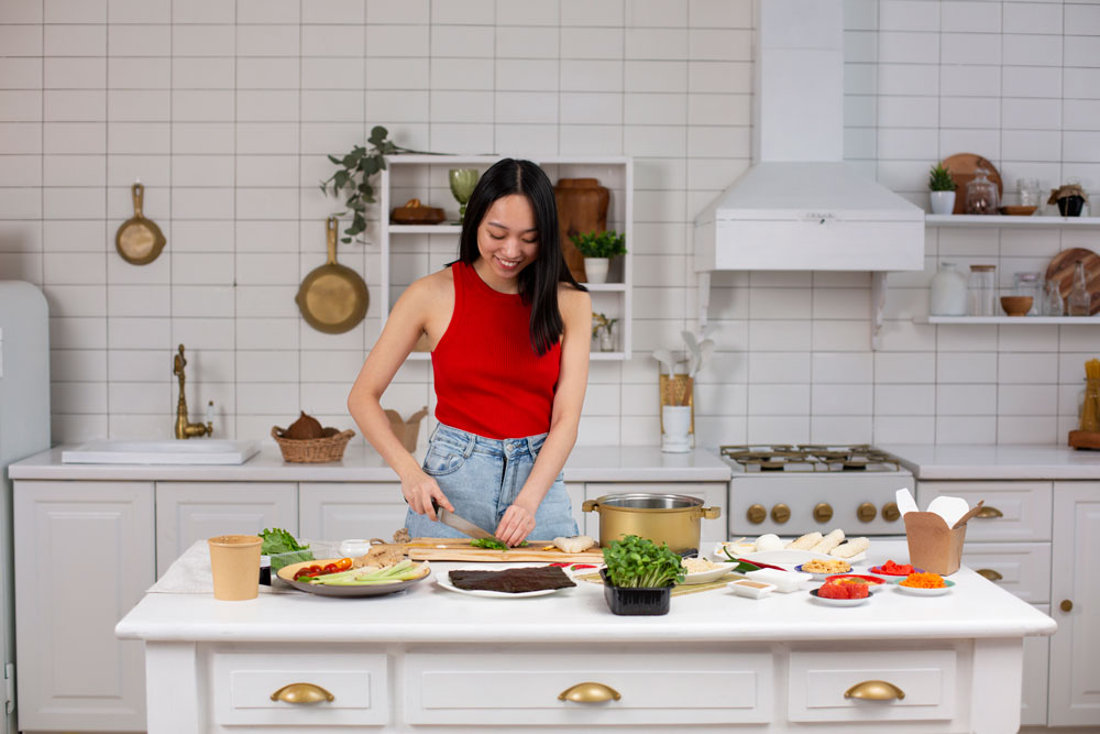 Seorang wanita berbaju merah sedang memasak di dapur.