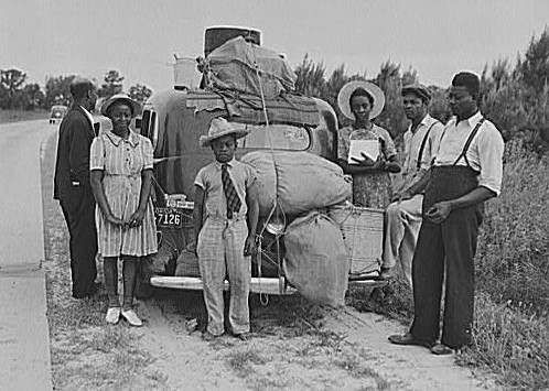 A group of people standing next to a car

Description automatically generated