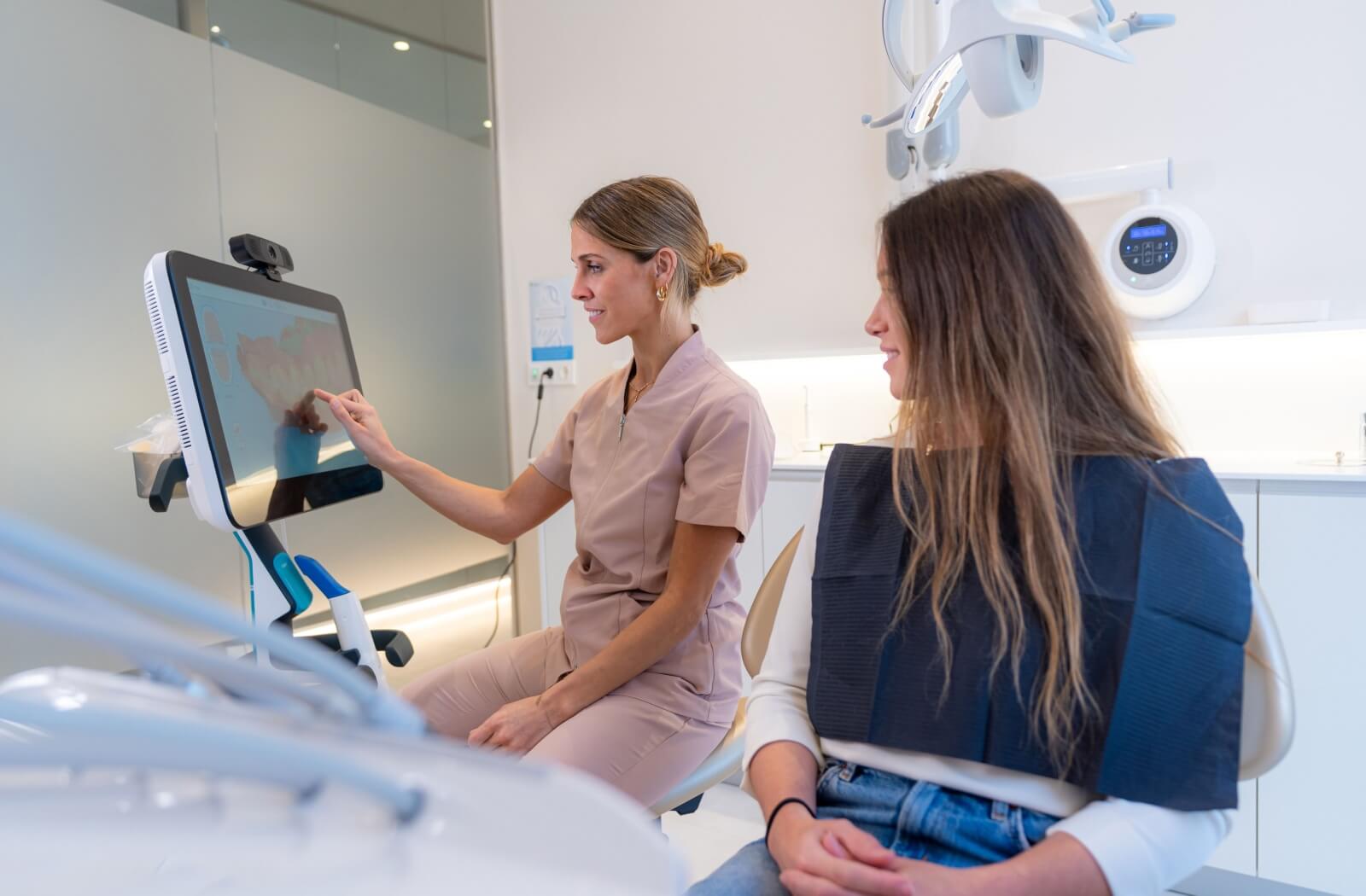 A dentist shows her patient the results of the digital imaging of her teeth.