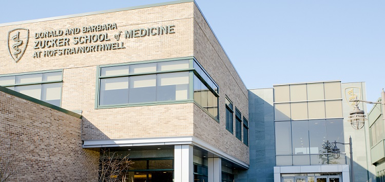 An image of the Hofstra University Zucker School of Medicine Research Institute building, featuring a modern glass exterior with the school name and logo on the front.