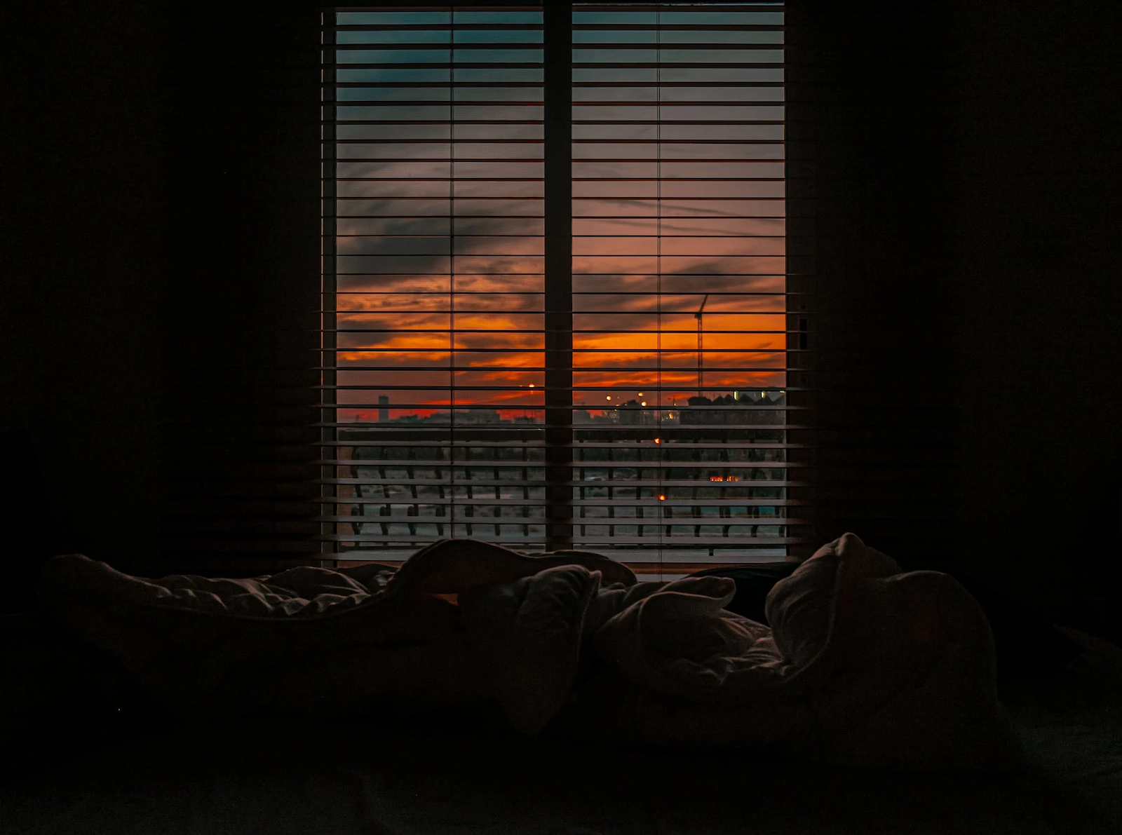 A dark bedroom with the sunset in the background