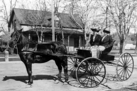 A horse drawn carriage with a couple of men

Description automatically generated