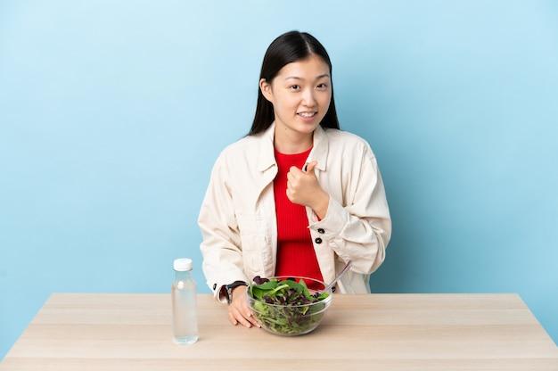 Premium Photo | Young chinese girl eating a salad having doubts while  scratching head