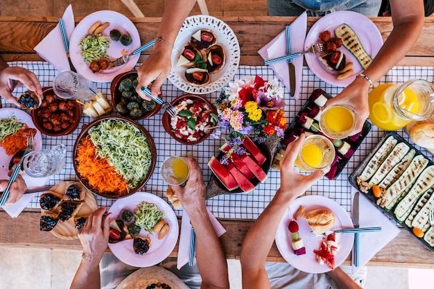 Premium Photo | Friendhsip and family celebration at lunch time in top  vertical view group of people eating together on the table people taking  food from dishes and enjoy time having fun