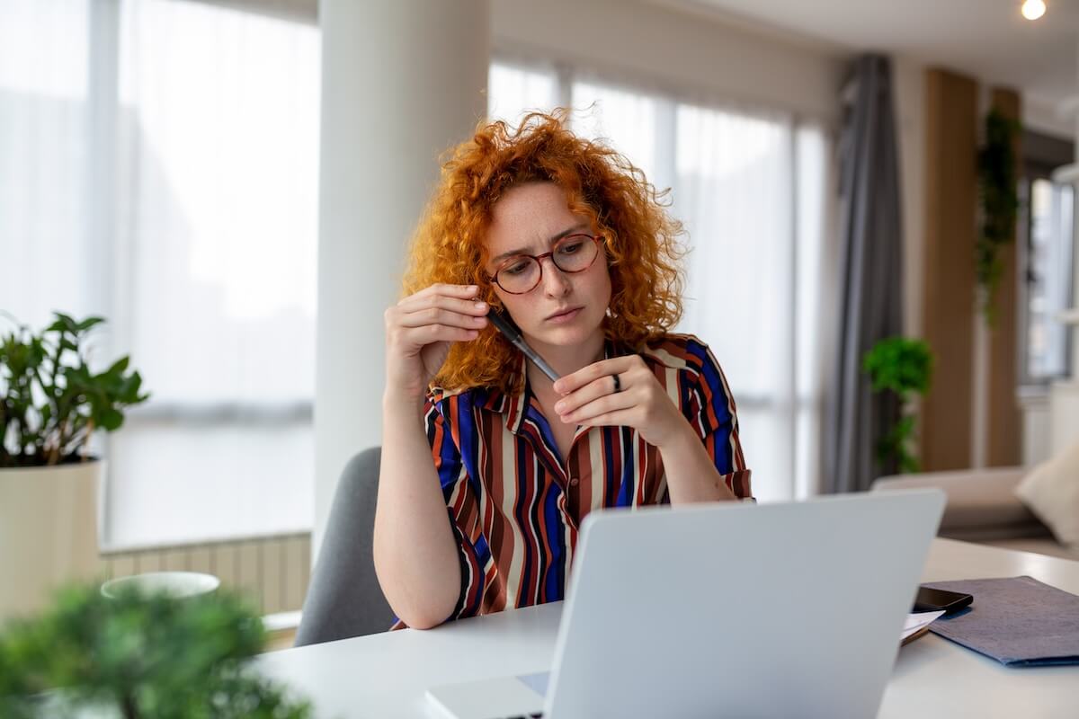 Employee holding a pen while looking at her laptop