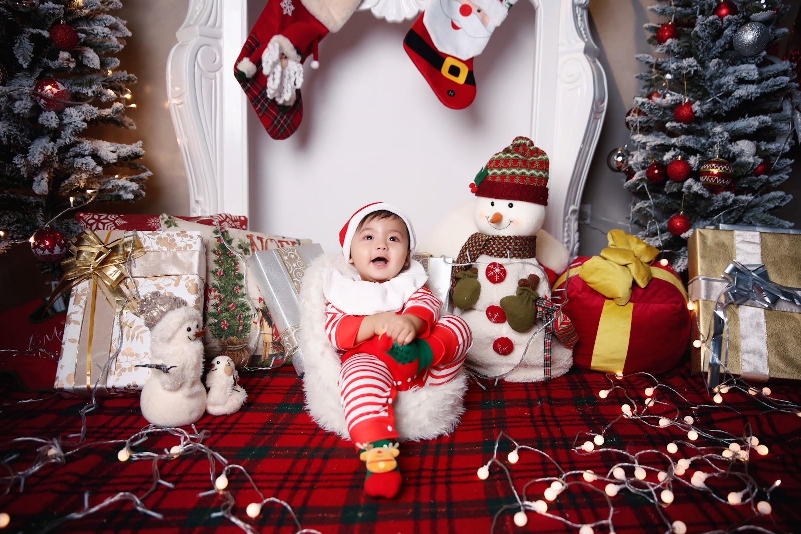 newborn christmas photo idea: newborn dressed up as a Christmas elf, lying on a bed or seating on a sofa bed