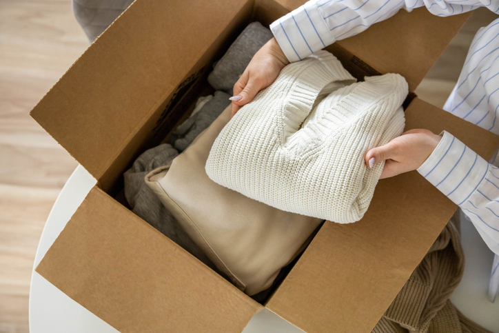 Closeup of young woman packing winter clothing into a storage box.