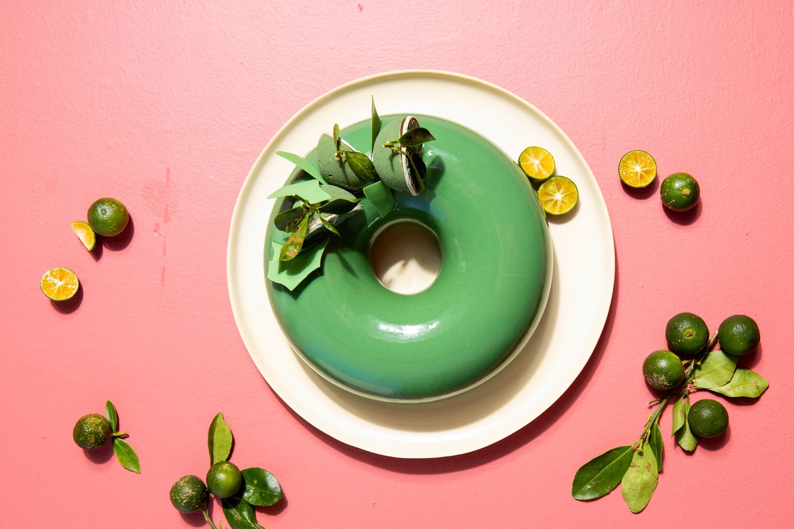 Dozens of green calamansi fruits beside calamansi powder and bowl full of same powder, both placed on top of a rectangular wooden serving board