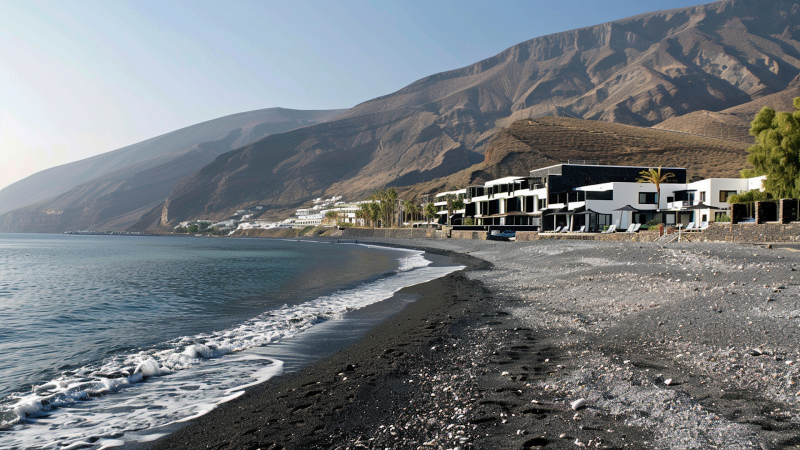 Beachfront hotels and villas with the mountains in the background in Santorini