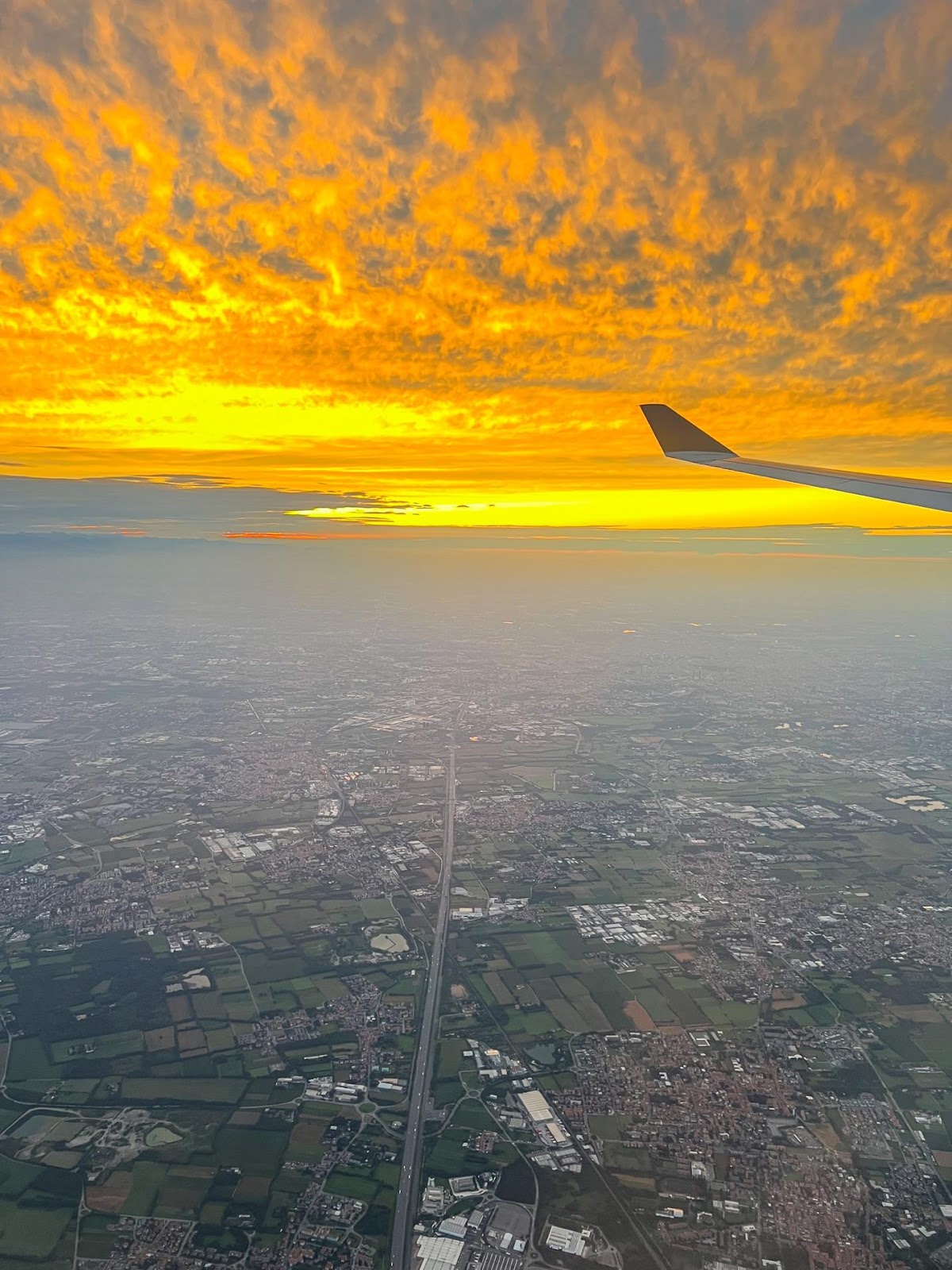 An airplane wing above a city

Description automatically generated