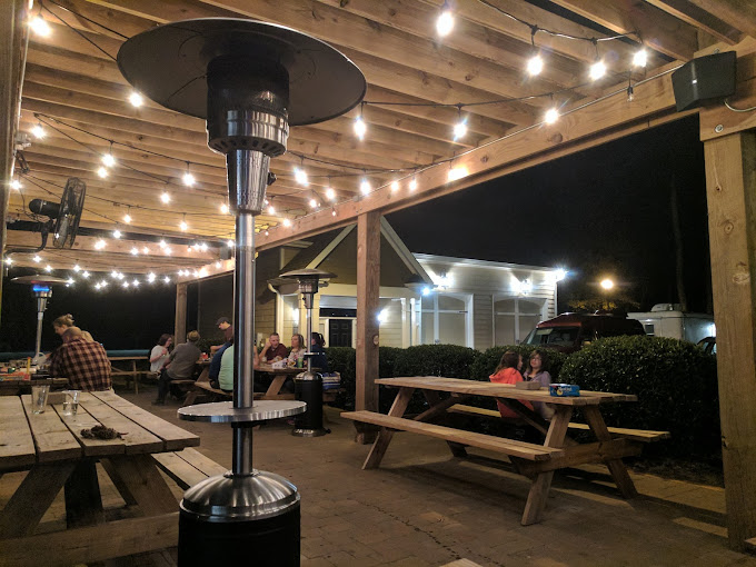 outdoor view of Oak City Brewing close up patio with picnic tables and string lights