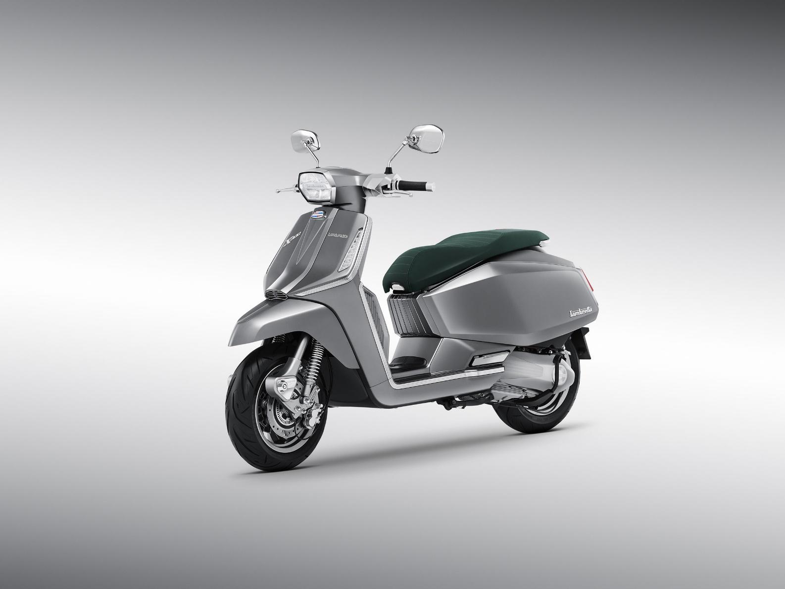 A silver scooter with a green seat
Description automatically generated