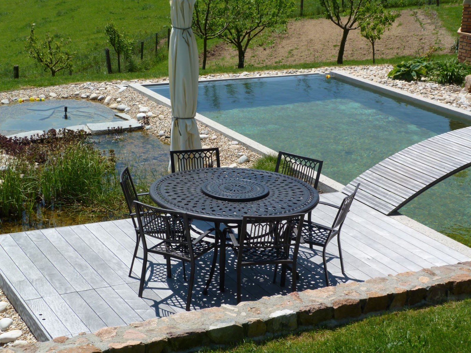 Schwarze Terrassenmöbel bestehend aus Gartentisch und Stühlen auf Terrasse neben Pool.
