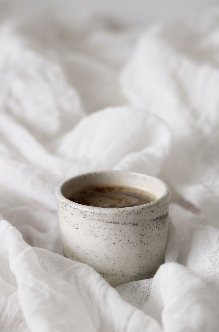 Cup of coffee on sheets on a bed
