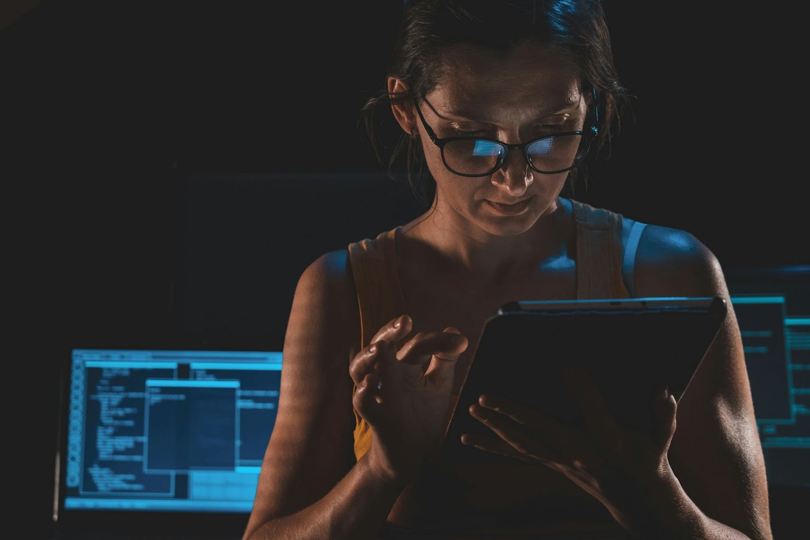Woman looking at a tablet, with editing software in the backdrop, suggesting deepfake scam analysis