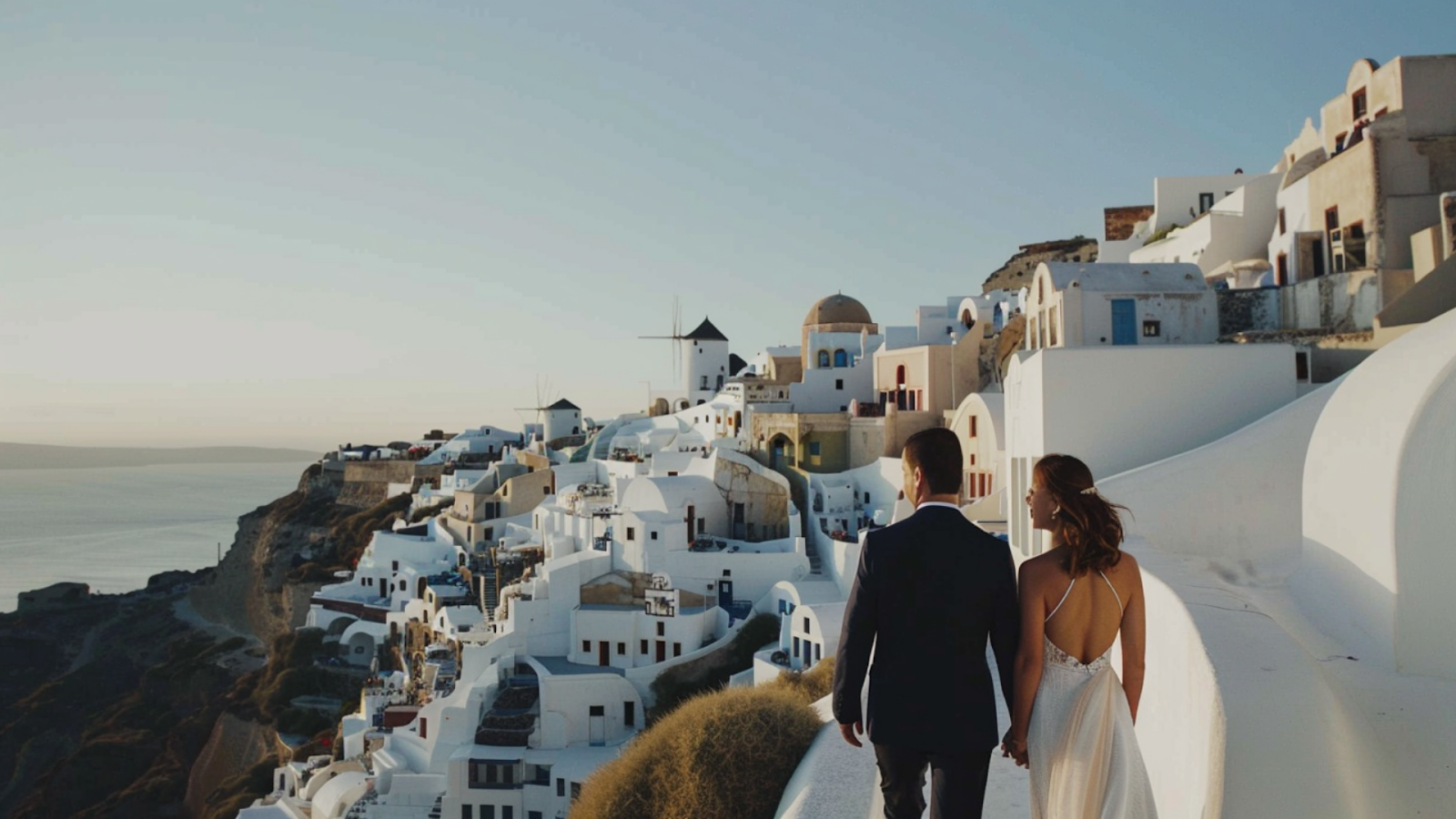 A newly-wed couple standing before the white-washed buildings in Santorini