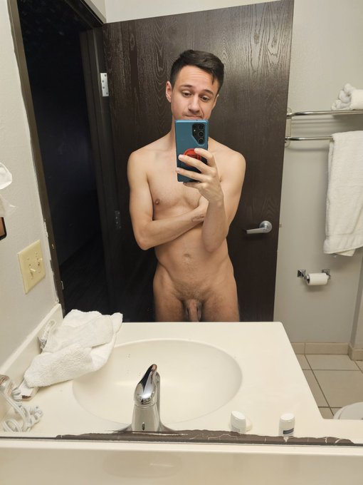 Dakota Wonders standing in the bathroom mirror taking a selfie naked showing off his flaccid cock