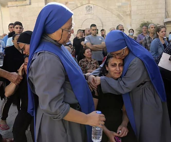 Sisters María del Pilar and María del Perpetuo Socorro comforting a woman who lost family in Israeli airstrikes.