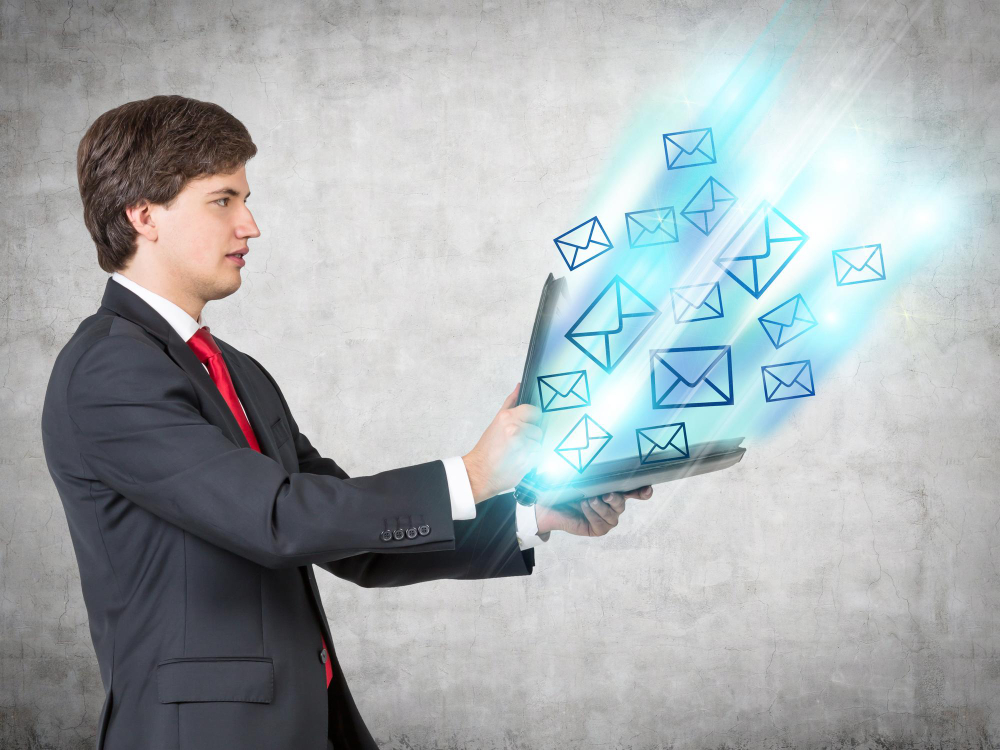 Person using a laptop with graphical icons of envelopes floating above the keyboard, symbolizing email communication or internet messaging.- Cliqly Email Marketing