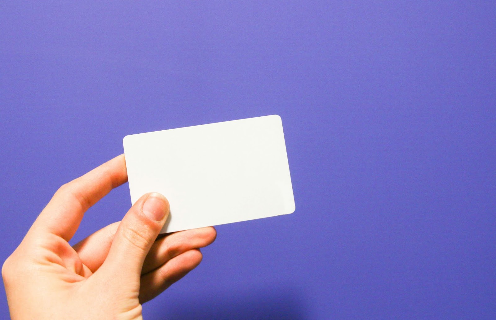 a hand holding a white card on a blue background