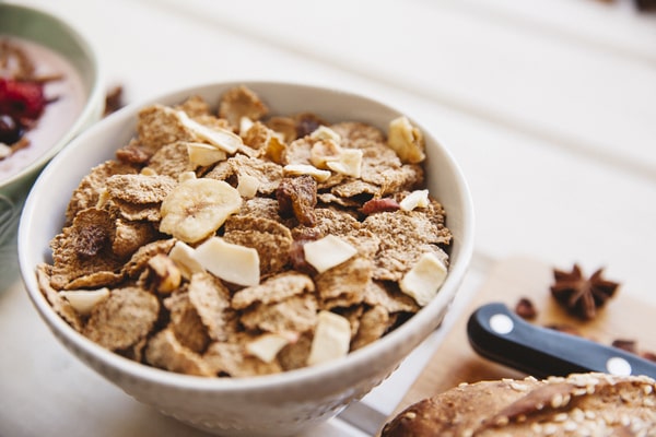 A bowl of cereals made of cornflakes, almond flakes, and banana flakes