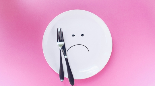 sad and empty plate on a pink background