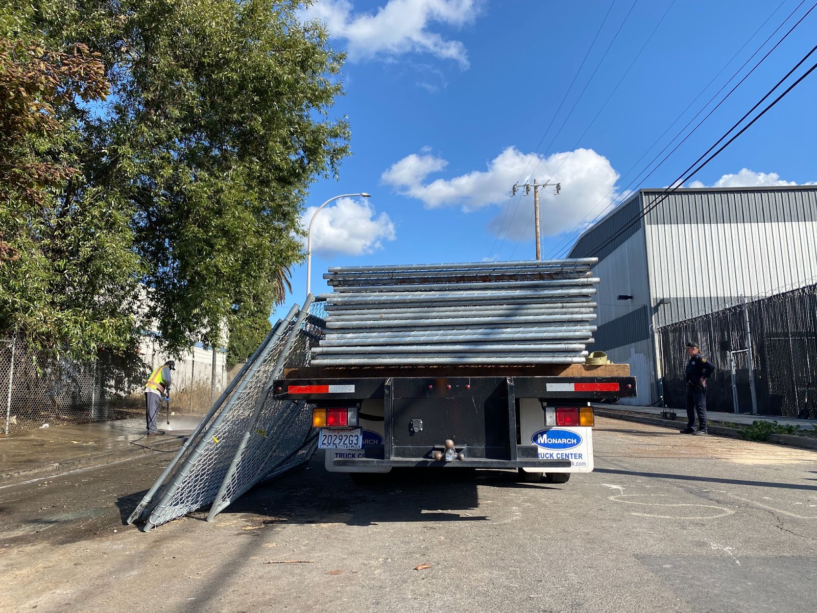 Berkeley Public Works Department pressure washes the sidewalk on Harrison Street to prepare for the installation of chain link fence panels, November 7, 2023. (Bradley Penner)