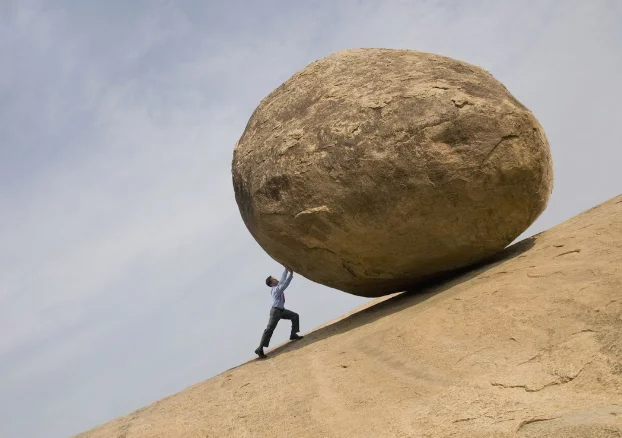 A person pushing a large rock</p>
<p>Description automatically generated