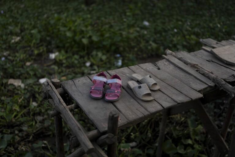 Do Bao Tran's pink sandals are placed next to her grandmother's on a weathered bridge that connects the land to their shanty houseboat in Can Tho, Vietnam, Wednesday, Jan. 17, 2024. After their mother left to pursue better financial opportunities in Ho Chi Minh City, Tran and her twin brother remained in the care of their grandmother, who supports the family by selling steamed buns at a floating market. (AP Photo/Jae C. Hong)