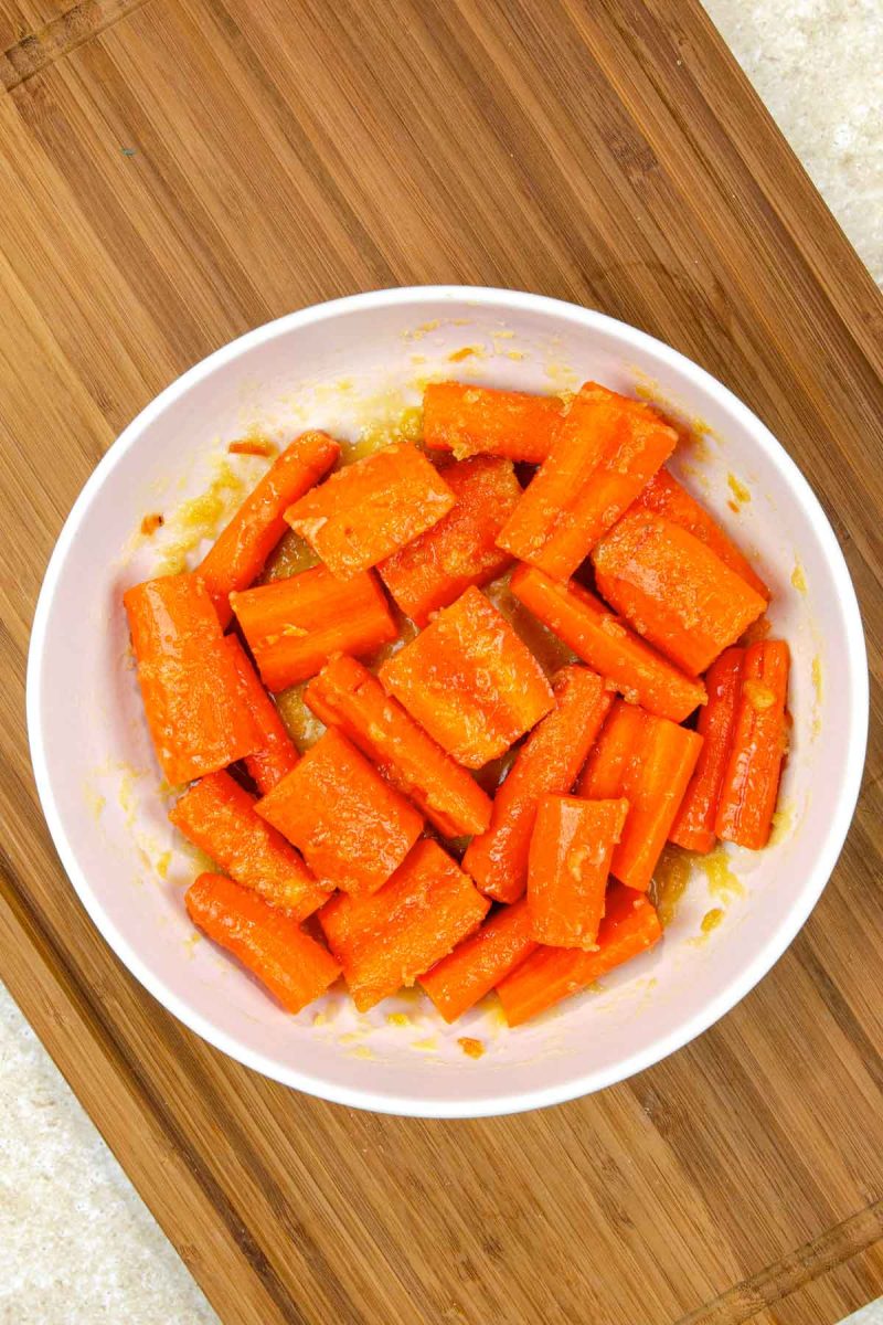 A bowl of air fryer carrots on a cutting board.
