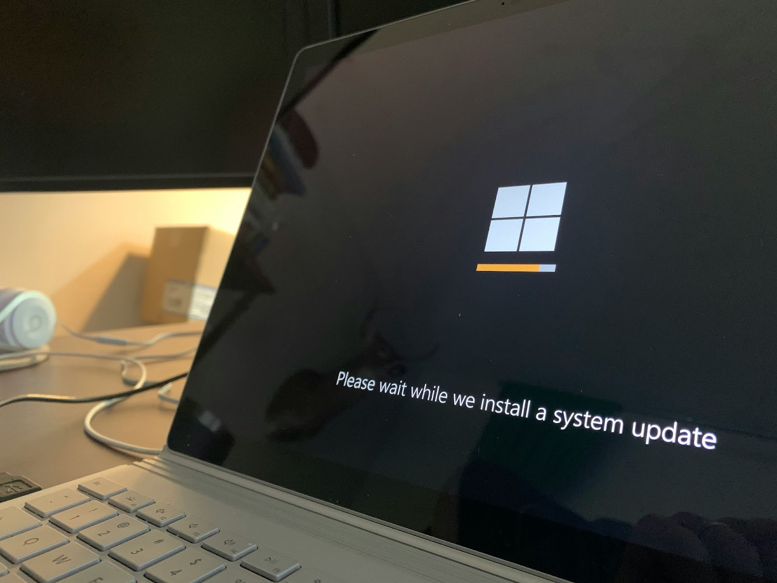 A laptop screen displaying an operating system update progress with the message "Please wait while we install a system update."