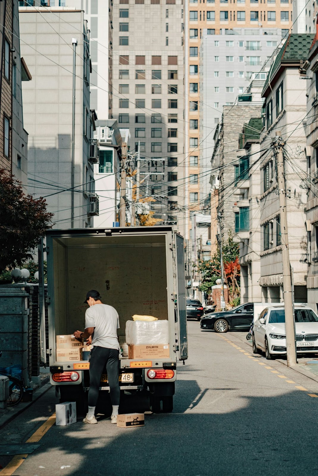 A person loading items on to a box truck next to high-rise buildings