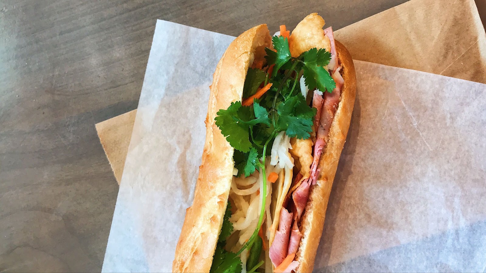 Banh Mi, a Vietnamese sandwich, with cilantro, carrot sticks, meat and veggies on a baguette