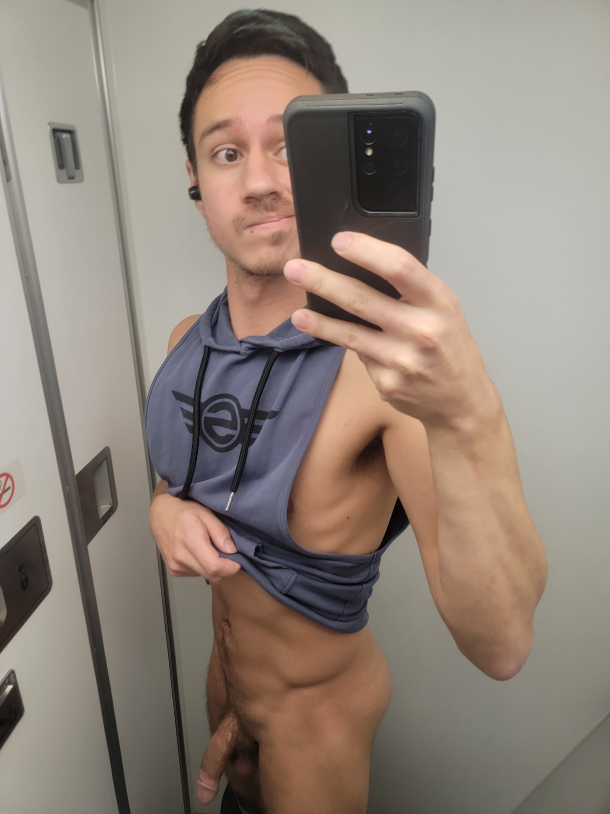 Dakota Wonders taking a pantless selfie in the airplane bathroom lifting up his sleeveless workout hoodie and showing off his flaccid penis