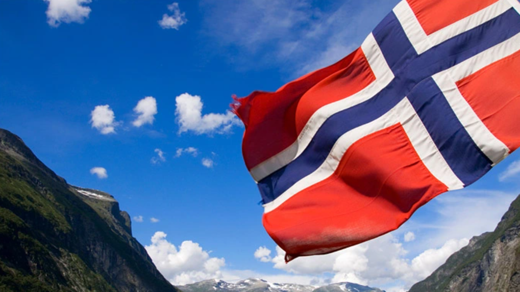 Norsk flagg med fjell i bakgrunnen