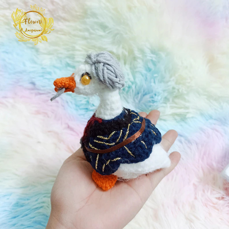 A promotional image of the Astarion goose crochet doll from FlowerAmigurumi on Etsy. 