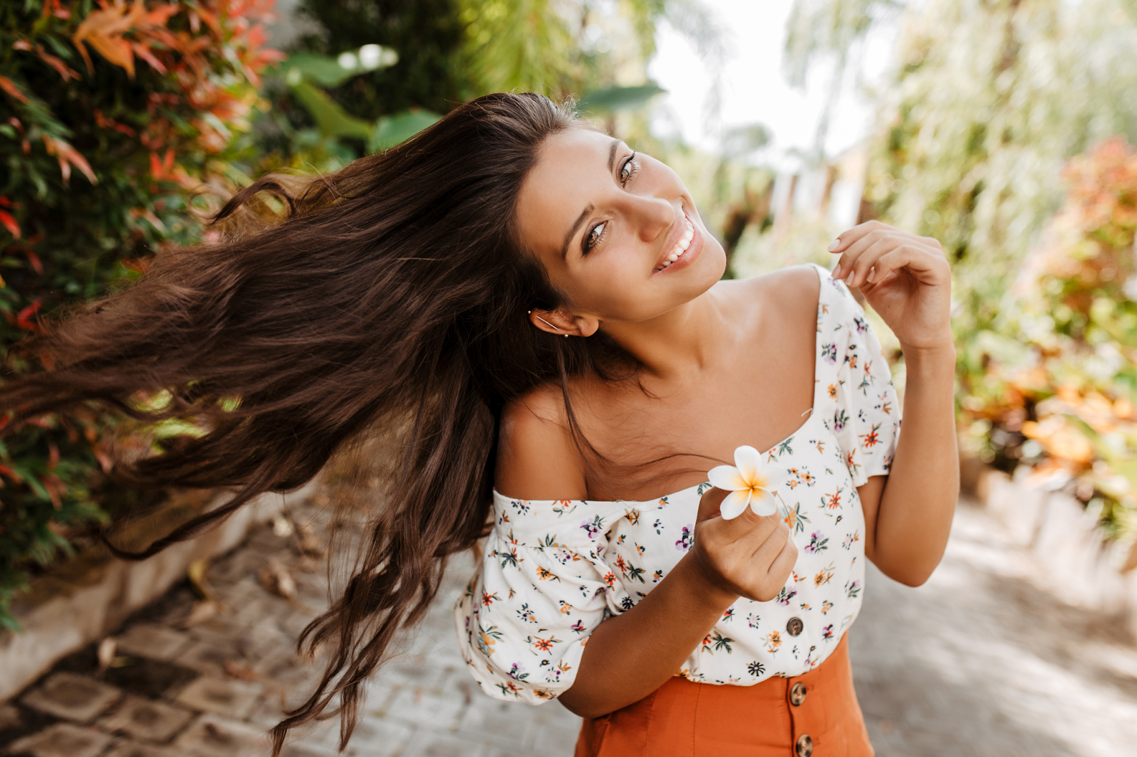 garota com expressão sorridente para a foto usando um look floral