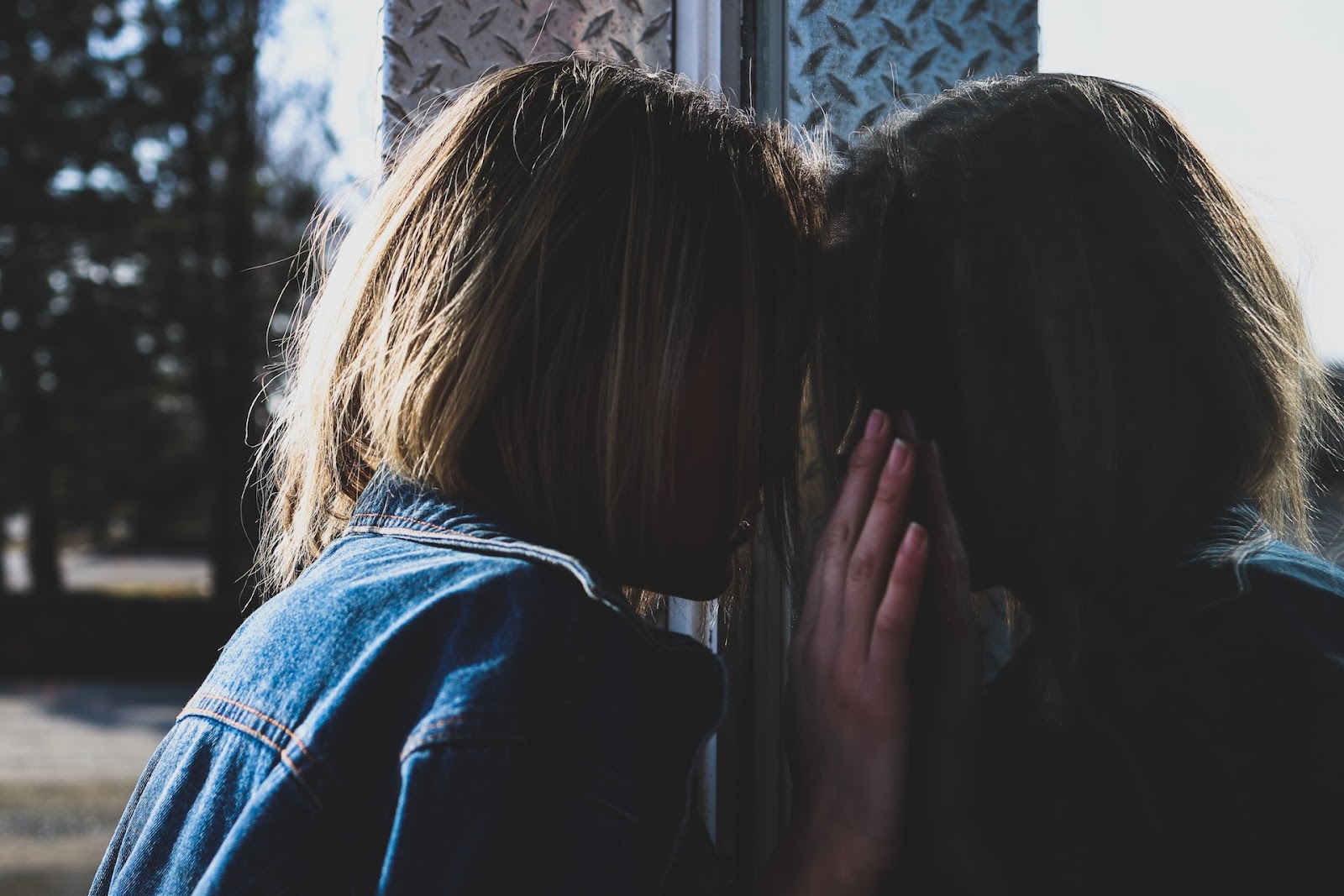 Woman looks at her reflection after experiencing emotional cheating