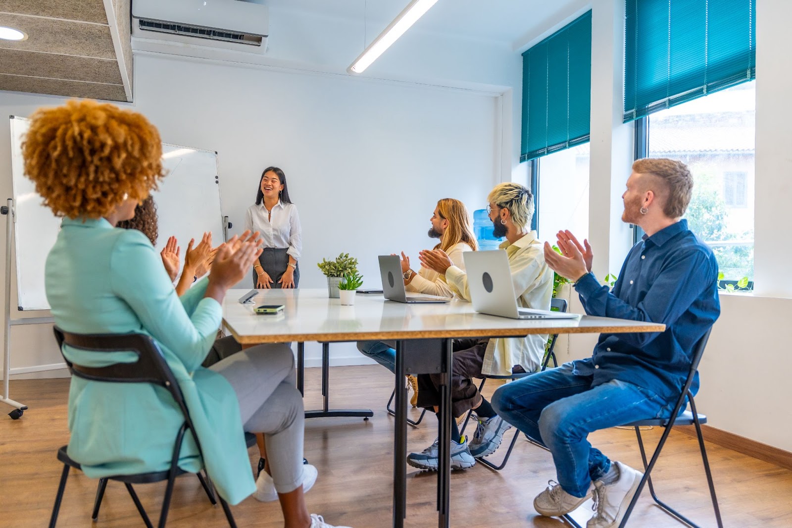 Co-workers applaud a woman after discussing a business proposal.