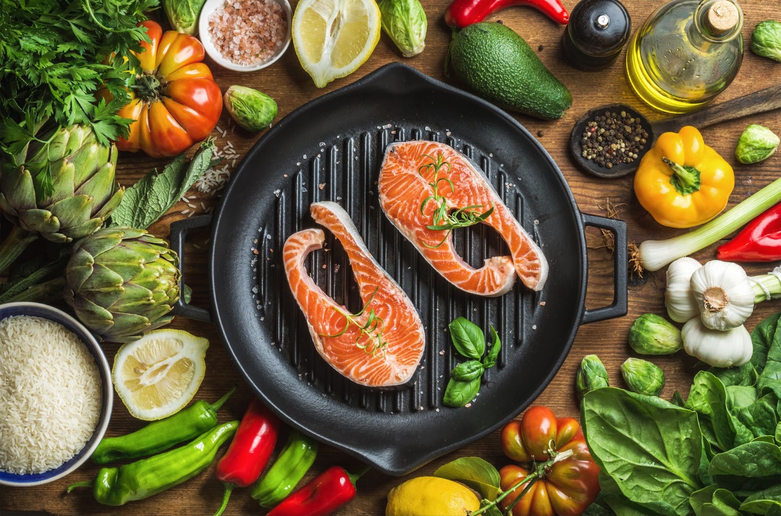 fish on cast iron surrounded by veggies and oils