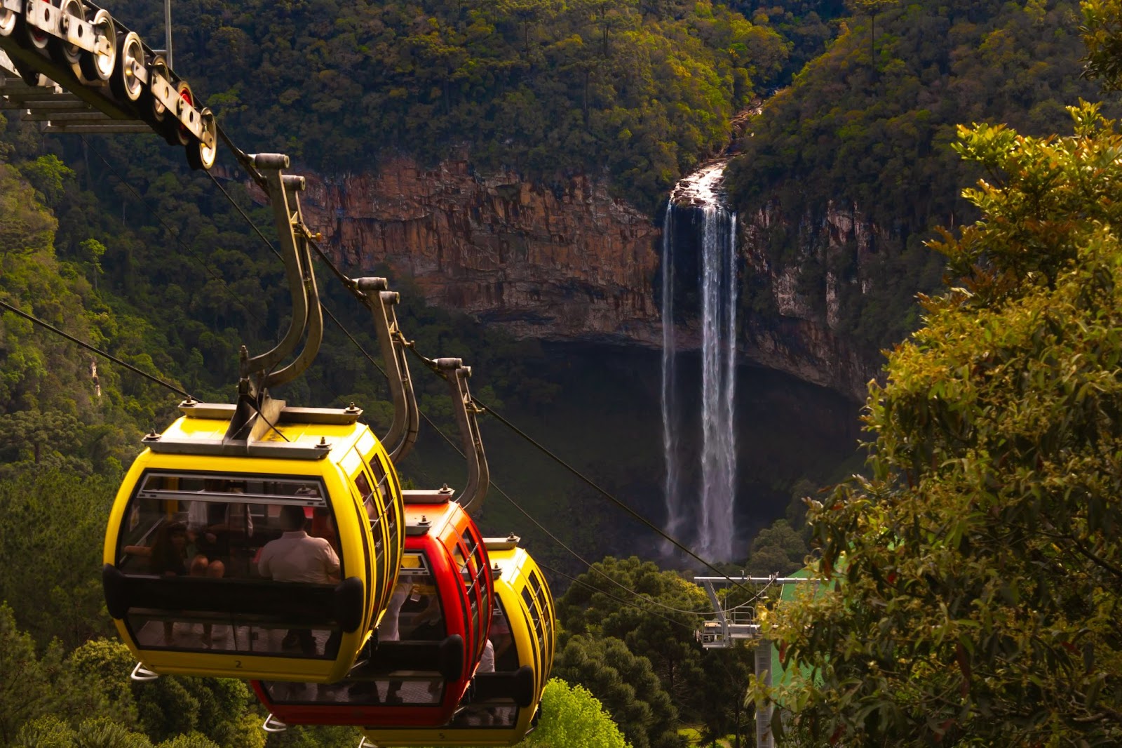 Bondinhos aéreos coloridos descendo em direção à Cascata do Caracol.