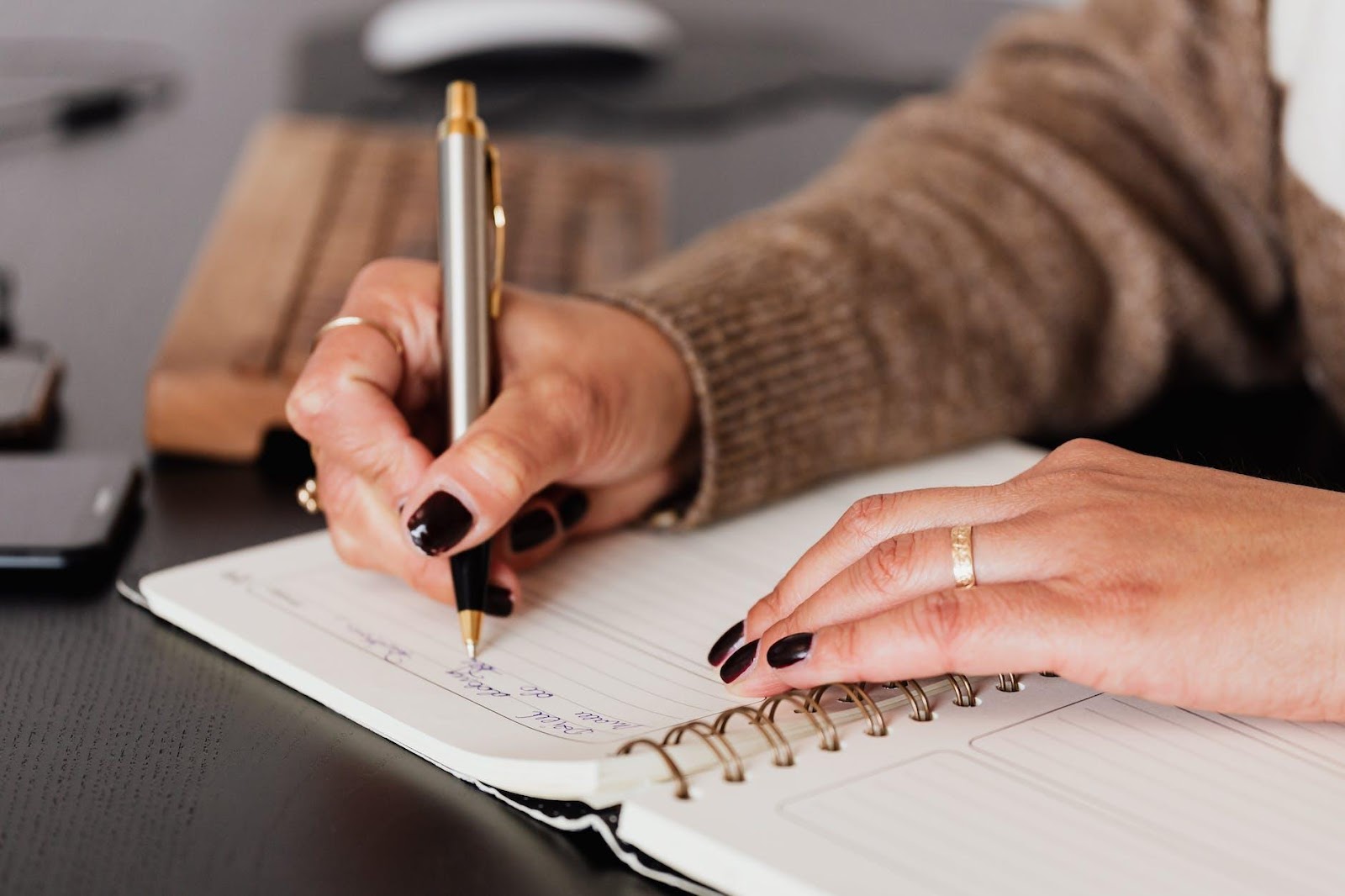 Crop unrecognizable female with stylish manicure sitting at black desk