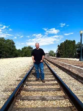 A person standing on train tracks

Description automatically generated