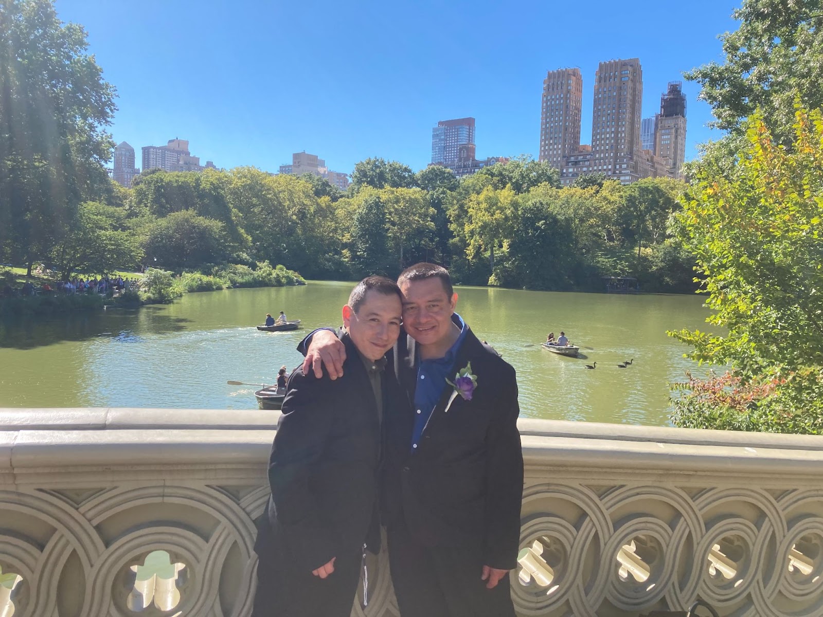 A couple stand hugging on a bridge in Central Park