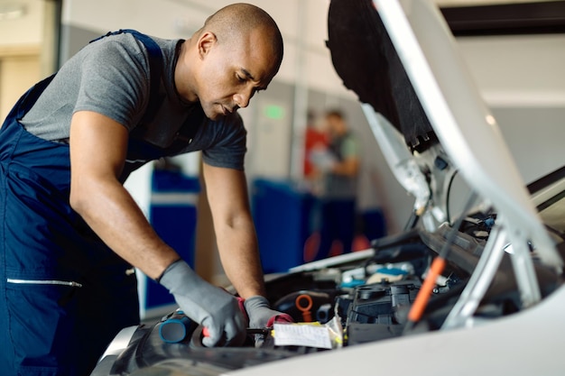 Mechanic repairing car engine in a workshop