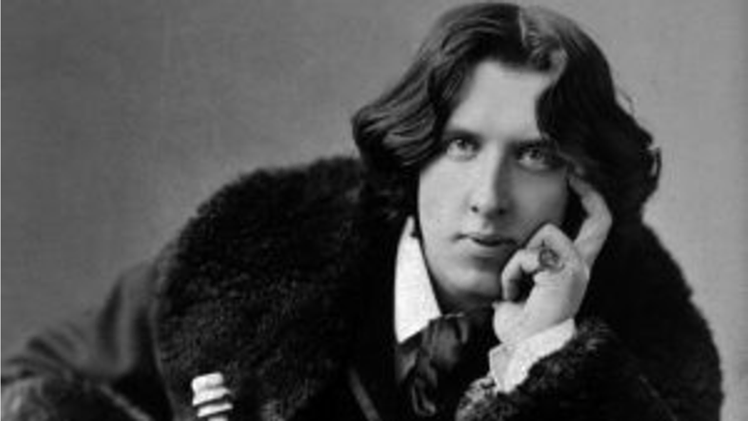 Image of Oscar Wilde in a fur coat with a ring.