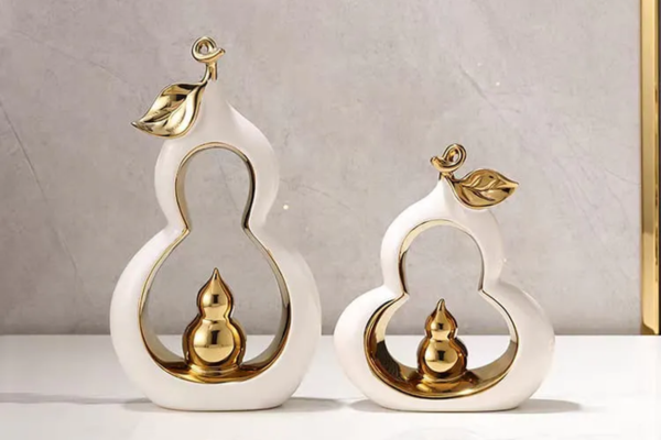 Small white pear-shaped decoration made of ceramic and resin with gold accents.