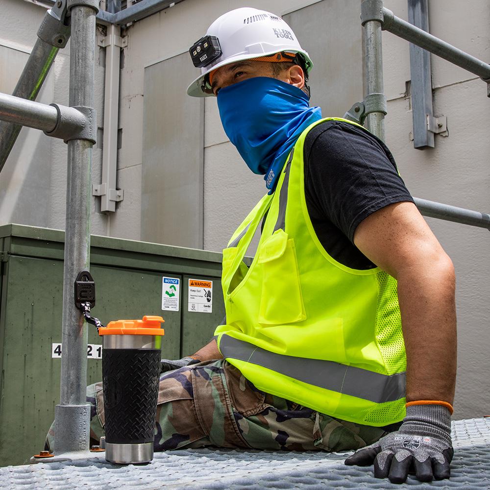 A person wearing a safety vest and a helmet sitting on a metal platform

Description automatically generated