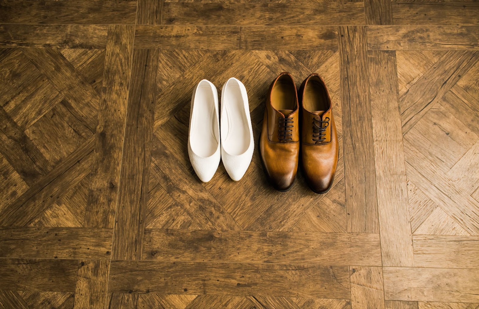 Two pairs of shoes on a wood floor. 