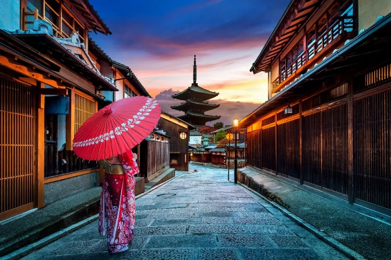 A person in a kimono holding a red umbrella

Description automatically generated